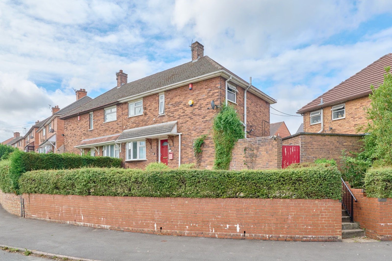 Brick family house behind a hedge