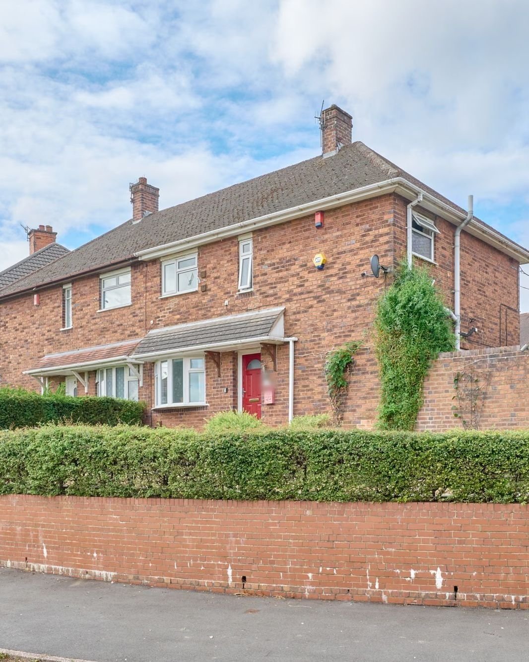 Red-brick semi-detached house behind a hedge