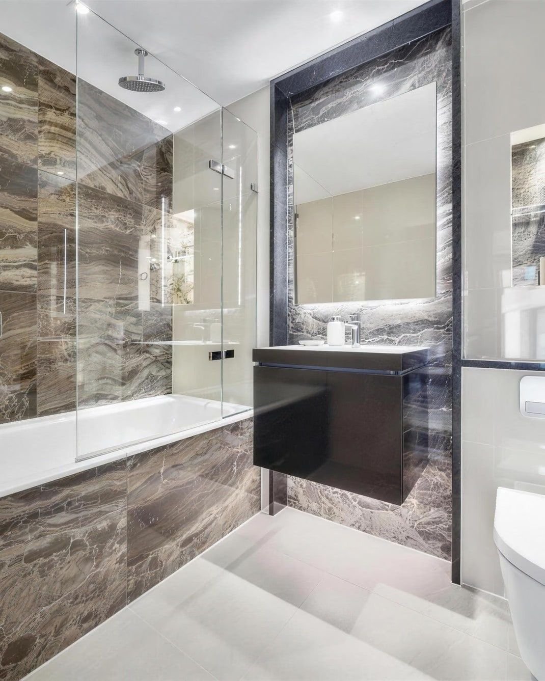 Marble-tiled bathroom with a glass shower screen and a wall-hung basin