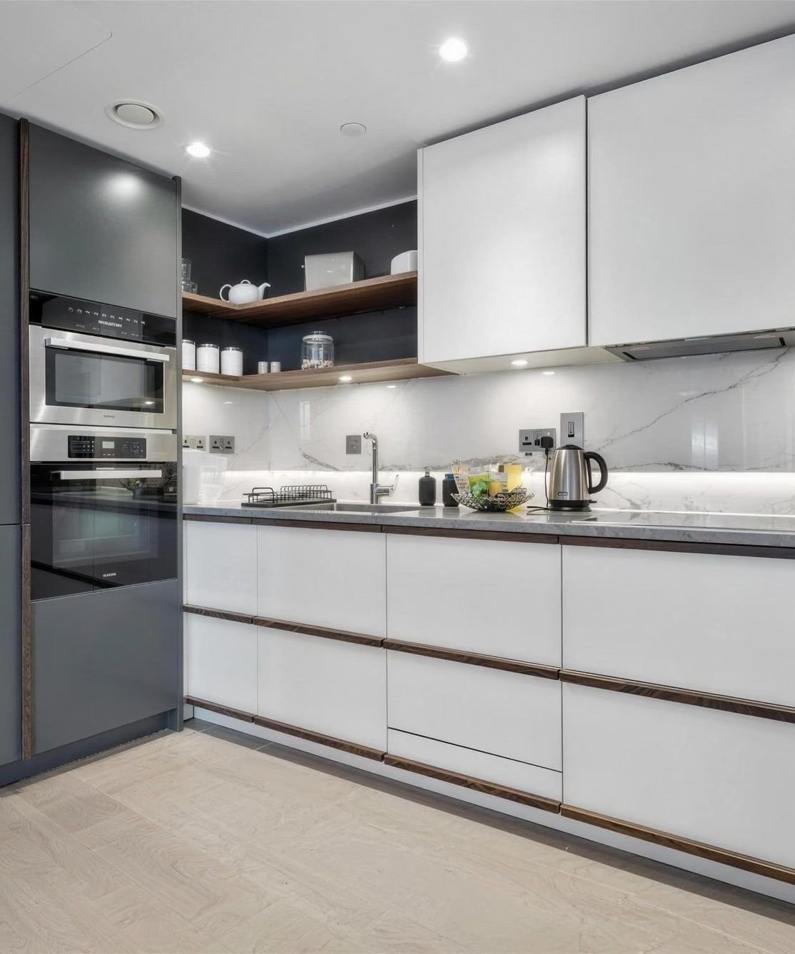 Kitchen with white cabinets and a marble splashback in The Paddington Apartment